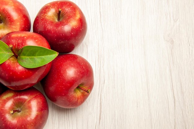 Vue de dessus pommes rouges fraîches fruits mûrs et moelleux sur un bureau blanc couleur des fruits frais de nombreux arbres végétaux