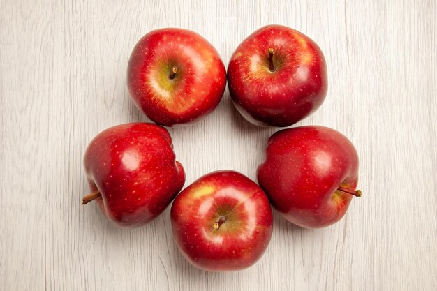 Vue de dessus pommes rouges fraîches fruits mûrs et moelleux sur un bureau blanc couleur des fruits plante fraîche arbre rouge