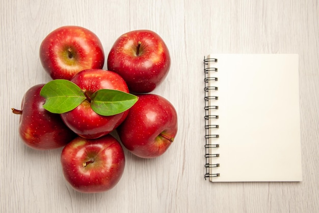 Vue de dessus pommes rouges fraîches fruits mûrs et moelleux sur un bureau blanc couleur des fruits des plantes arbre rouge frais