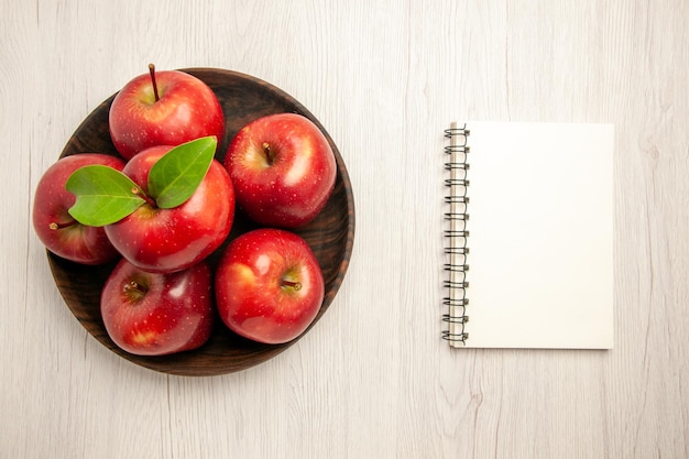 Vue de dessus pommes rouges fraîches fruits mûrs et moelleux sur bureau blanc fruits arbre de couleur rouge plante fraîche