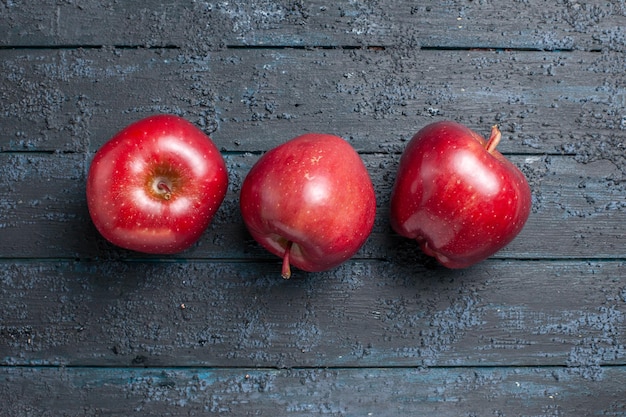 Photo gratuite vue de dessus pommes rouges fraîches fruits mûrs et moelleux sur le bureau bleu foncé de nombreux arbres fruitiers couleur rouge des plantes fraîches