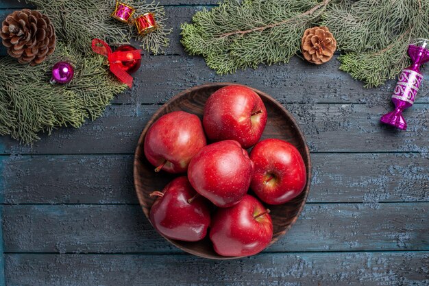 Vue de dessus pommes rouges fraîches fruits mûrs moelleux sur le bureau bleu foncé plante de nombreux fruits vitamine rouge couleur fraîche