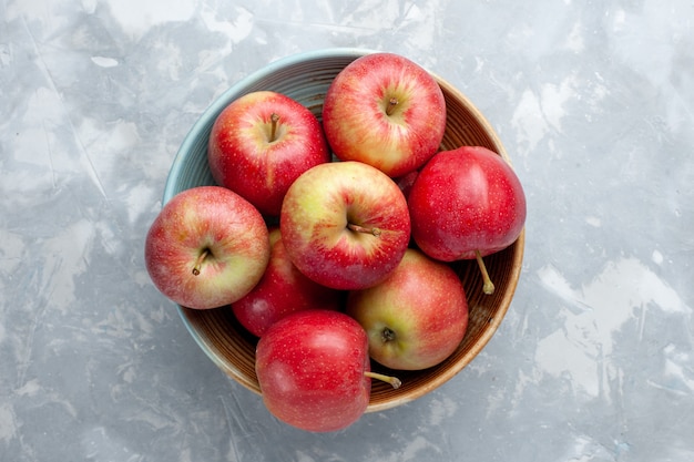 Vue de dessus pommes rouges fraîches à l'intérieur de la plaque sur fond blanc fruits frais mûrs mûrs vitamine