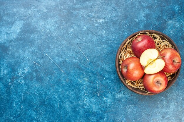 Vue de dessus pommes rouges fraîches à l'intérieur de la plaque sur la table bleue photo couleur mûre arbre vie saine poire fruit place libre