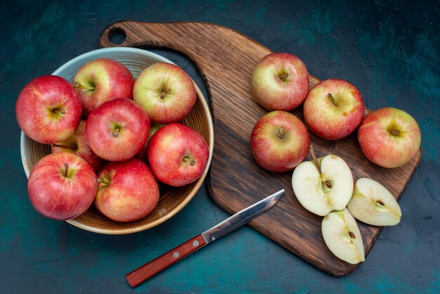 Vue de dessus pommes rouges fraîches juteuses et moelleuses à l'intérieur de la plaque sur la surface bleu foncé fruits frais mûrs moelleux