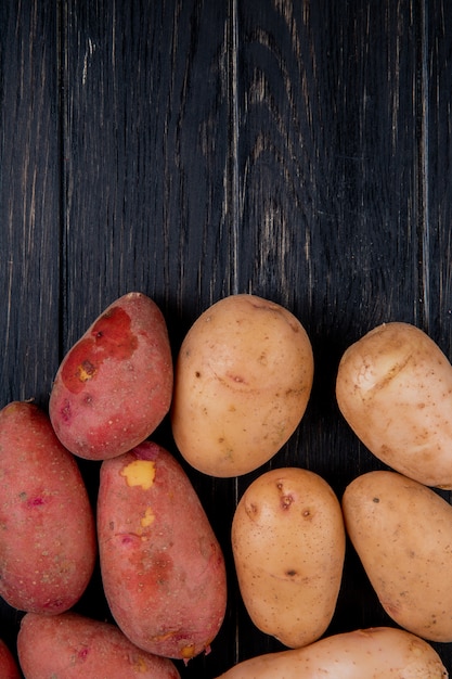 Vue de dessus des pommes de terre blanches et rouges sur une surface en bois avec copie espace