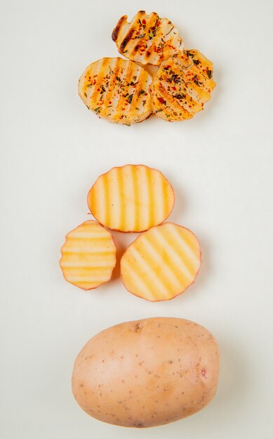 Vue de dessus de pommes de terre entières tranchées et frites sur une surface blanche