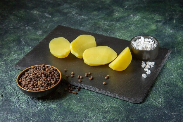 Vue De Dessus Des Pommes De Terre Fraîches Coupées Sur Une Planche à Découper En Bois Et épices Sur Fond De Couleurs De Mélange Noir Vert Avec Espace Libre