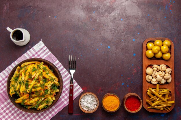 Vue de dessus des pommes de terre frites savoureuses frites avec des légumes verts et de l'huile sur le bureau sombre