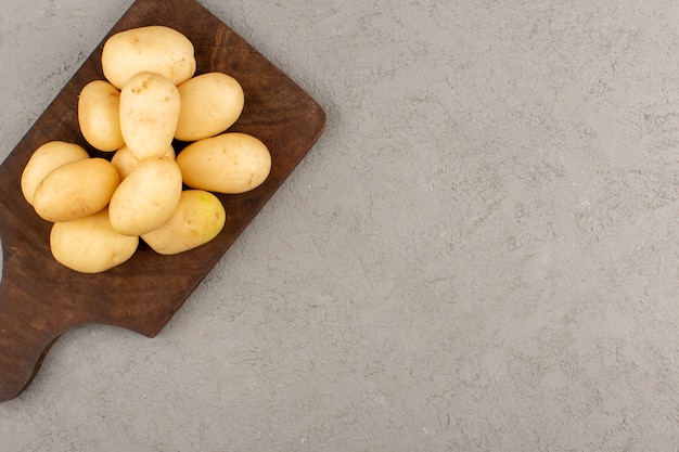 Vue de dessus des pommes de terre pelées sur le bureau en bois brun sur le gris