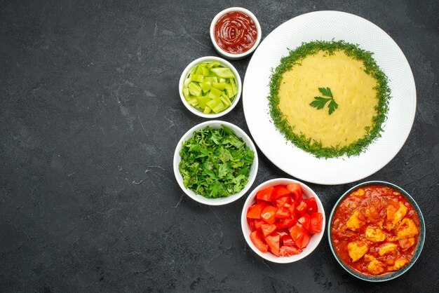 Vue de dessus des pommes de terre en purée avec des verts et des tomates sur gris