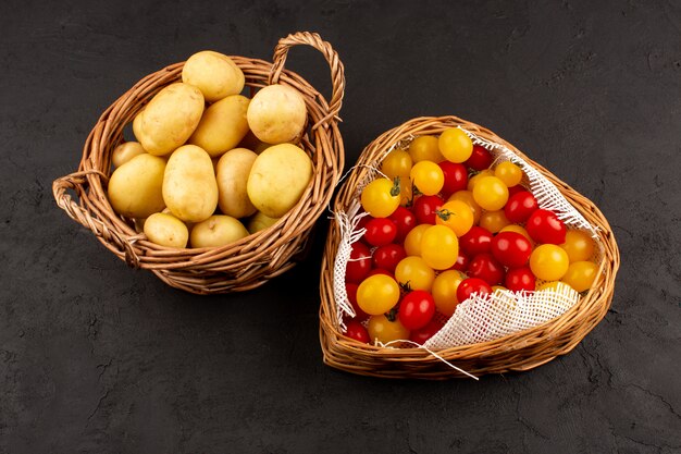 Vue de dessus des pommes de terre et des tomates à l'intérieur des paniers sur l'obscurité