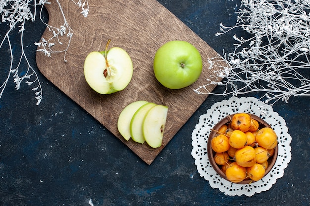 Vue de dessus des pommes vertes fraîches avec des cerises douces et moelleuses sur un bureau bleu foncé, des vitamines de fruits frais et moelleux