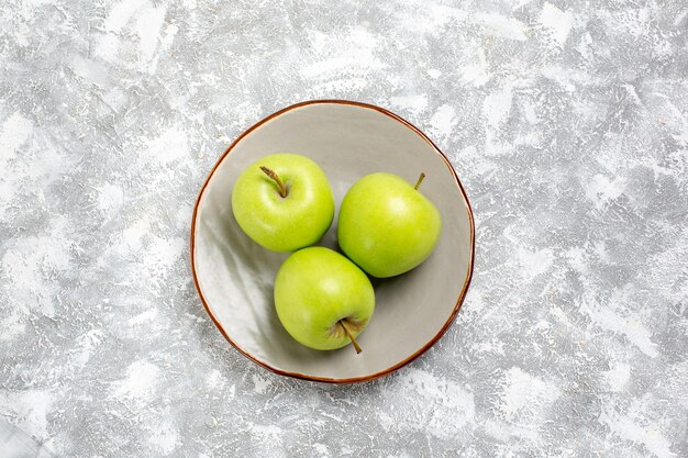 Vue de dessus des pommes vertes fraîches à l'intérieur de la plaque sur une surface blanche claire