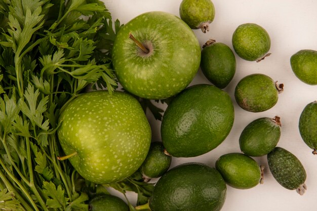 Vue de dessus des pommes vertes fraîches avec des limes feijoas et persil isolé sur un mur blanc