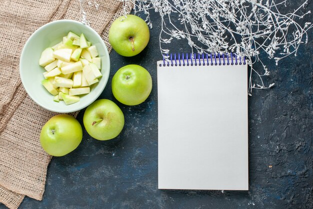 Vue de dessus des pommes vertes fraîches moelleuses et juteuses avec des tranches de pomme à l'intérieur de la plaque sur dark, fruits frais santé vitamine