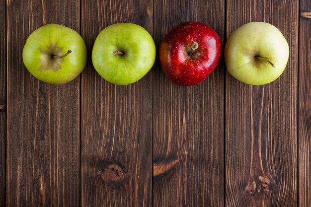 Vue de dessus des pommes vertes avec une rouge sur fond en bois. espace libre horizontal pour votre texte