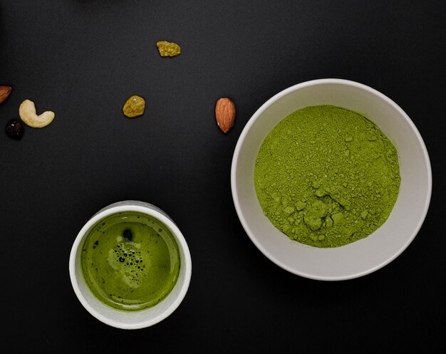 Vue de dessus de la poudre de thé matcha dans un bol avec un assortiment de noix