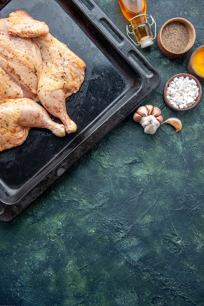 Vue de dessus poulet épicé frais avec des assaisonnements sur le fond bleu foncé alimentaire plat de poivrons d'épices dîner couleur de la viande sel cuisson