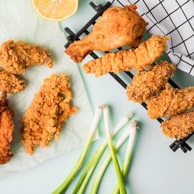 Vue de dessus de poulet frit sur plateau avec citron, oignons verts et torchon