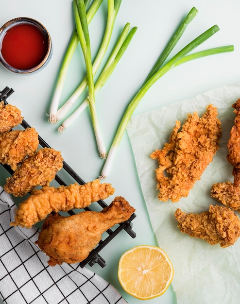 Vue de dessus poulet frit sur plateau avec sauce, oignons verts et citron