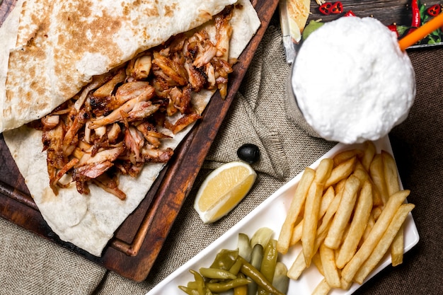Vue de dessus de poulet kebab avec pain plat servi avec des frites cornichons au citron et ayran