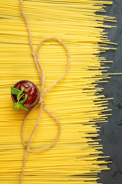 Vue de dessus pour les spaghettis crus et le ketchup dans une soucoupe sur fond noir