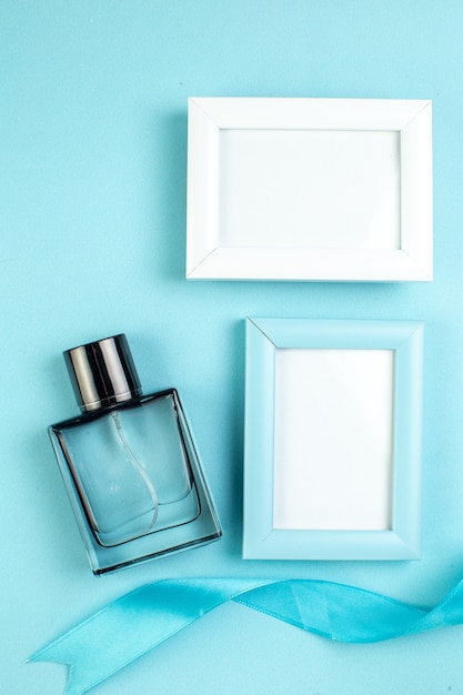 Photo gratuite la vue de dessus présente des cadres photo avec du parfum sur une surface bleue femme cadeau couple sentiment couleur parfum mariage amour