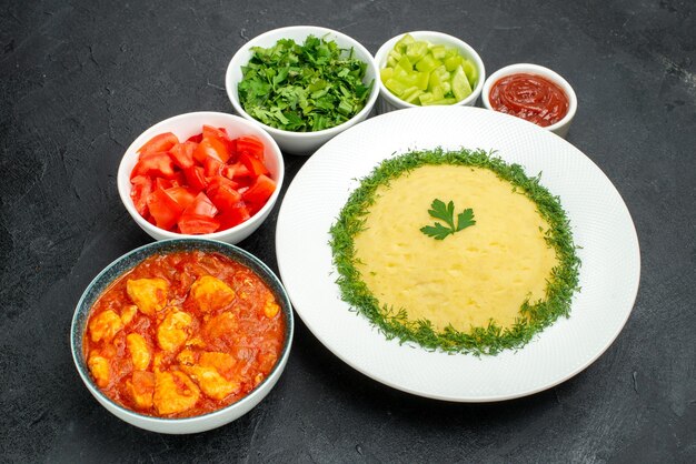 Vue de dessus de la purée de pommes de terre avec des légumes verts et des tranches de tomates sur une table grise