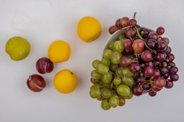 Vue de dessus des raisins dans un bol avec des pluots et des nectacots sur fond blanc