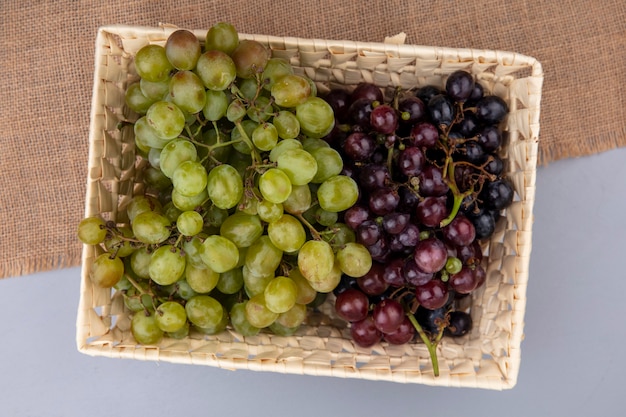 Vue de dessus des raisins dans le panier sur un sac sur fond gris