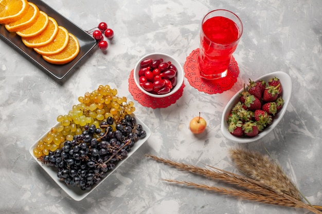 Photo gratuite vue de dessus des raisins frais avec des cornouillers et des fraises sur la surface blanche fruit berry tropical frais exotiques