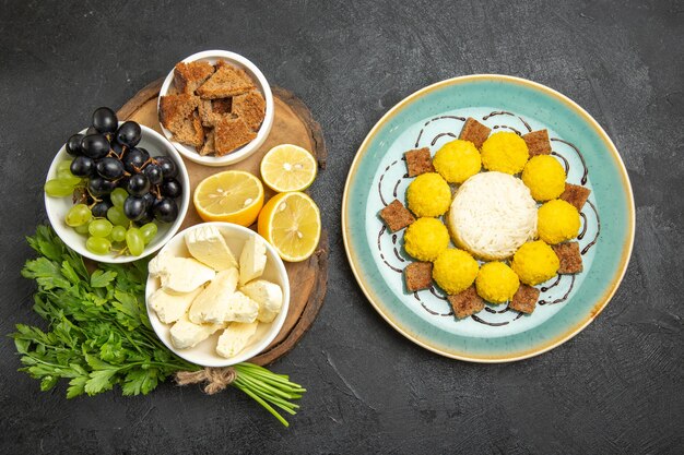 Vue de dessus des raisins frais avec du fromage blanc, des bonbons verts et du citron sur une surface sombre, des aliments au lait de fruits