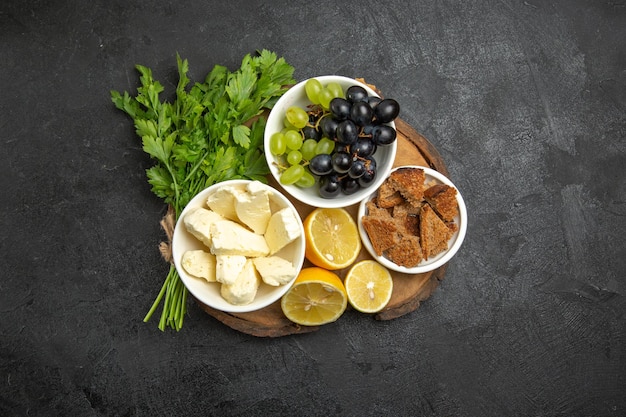 Vue de dessus des raisins frais avec du fromage blanc et des tranches de citron sur la surface sombre des aliments au lait de fruits