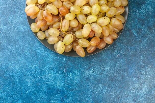 Vue de dessus des raisins frais à l'intérieur de la plaque sur la table bleue