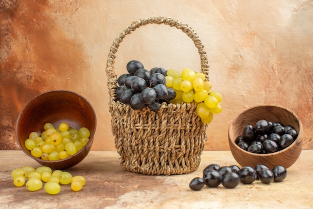 Vue de dessus des raisins frais noirs et jaunes tombés de petits pots et dans un panier