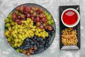 Photo gratuite vue de dessus des raisins frais avec une tasse de thé et de raisins secs sur la surface blanche fruit raisin thé frais