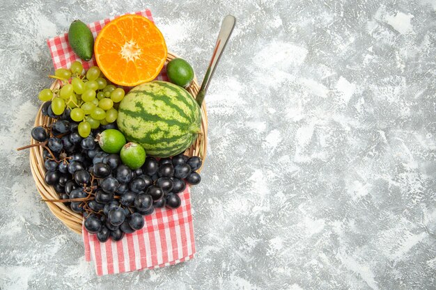 Photo gratuite vue de dessus des raisins noirs frais avec de l'orange et du feijoa sur une surface blanche, des fruits mûrs mûrs et mûrs