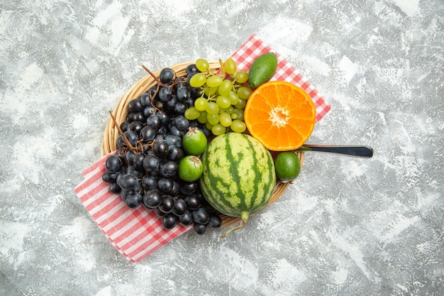 Vue de dessus des raisins noirs frais avec de l'orange et du feijoa sur une surface blanche, des fruits mûrs mûrs et mûrs