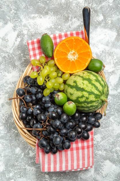 Vue de dessus des raisins noirs frais avec de l'orange et du feijoa sur une surface blanche, des fruits mûrs mûrs et mûrs