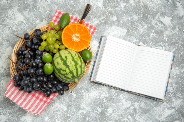 Vue de dessus des raisins noirs frais avec de l'orange et du feijoa sur une surface blanche, des fruits mûrs, des vitamines douces et fraîches