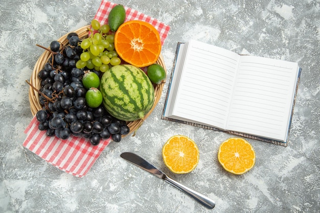 Vue de dessus des raisins noirs frais avec des oranges et du feijoa sur une surface blanche, des fruits mûrs, des vitamines douces, des arbres frais