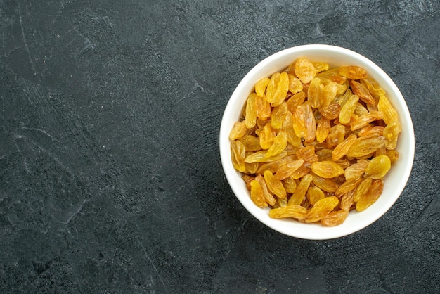 Vue de dessus des raisins secs à l'intérieur de la plaque blanche sur la surface sombre des raisins secs aigres séchés