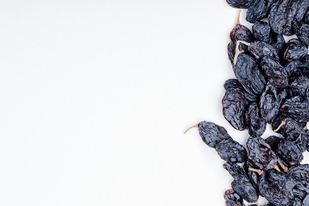 Vue de dessus des raisins secs noirs sur fond blanc avec copie espace