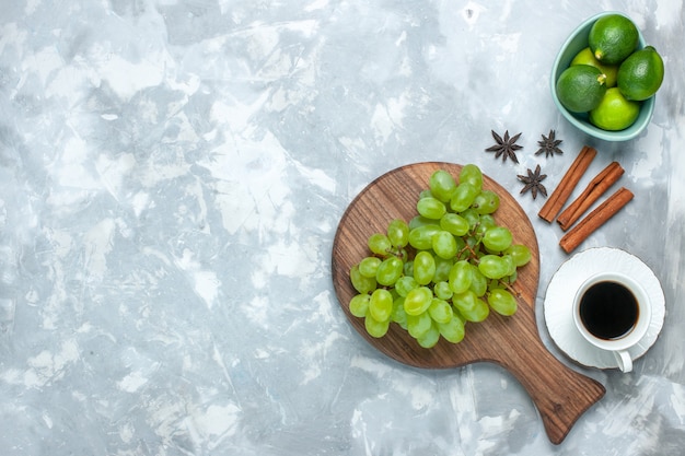 Vue de dessus des raisins verts frais fruits juteux moelleux avec des citrons de cannelle et du thé sur un bureau léger.