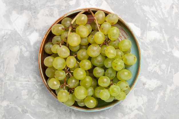 Vue de dessus des raisins verts frais à l'intérieur sur une surface blanche