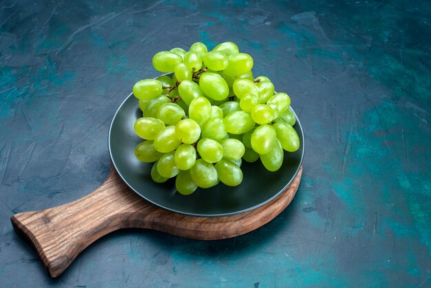 Vue de dessus des raisins verts frais moelleux fruits juteux à l'intérieur de la plaque sur le bureau bleu foncé.