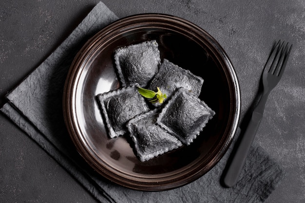 Vue de dessus des raviolis noirs sur une plaque avec une fourchette