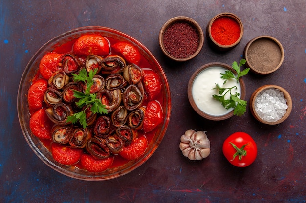 Photo gratuite vue de dessus repas de légumes cuits délicieux tomates et aubergines avec assaisonnements crème sure sur la surface sombre