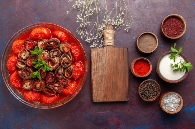 Vue de dessus repas de légumes cuits délicieux tomates et aubergines avec assaisonnements sur la surface sombre